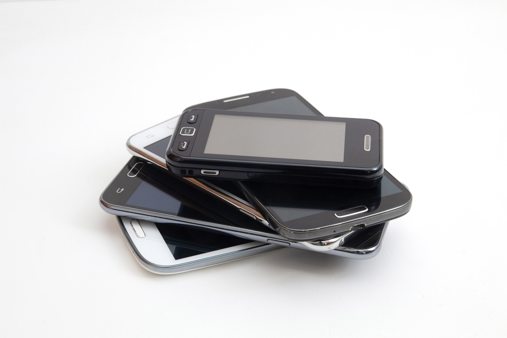 A stack of four inoperable smartphones, illustrating the need for bricking coverage as part of a Cyber Insurance policy. 