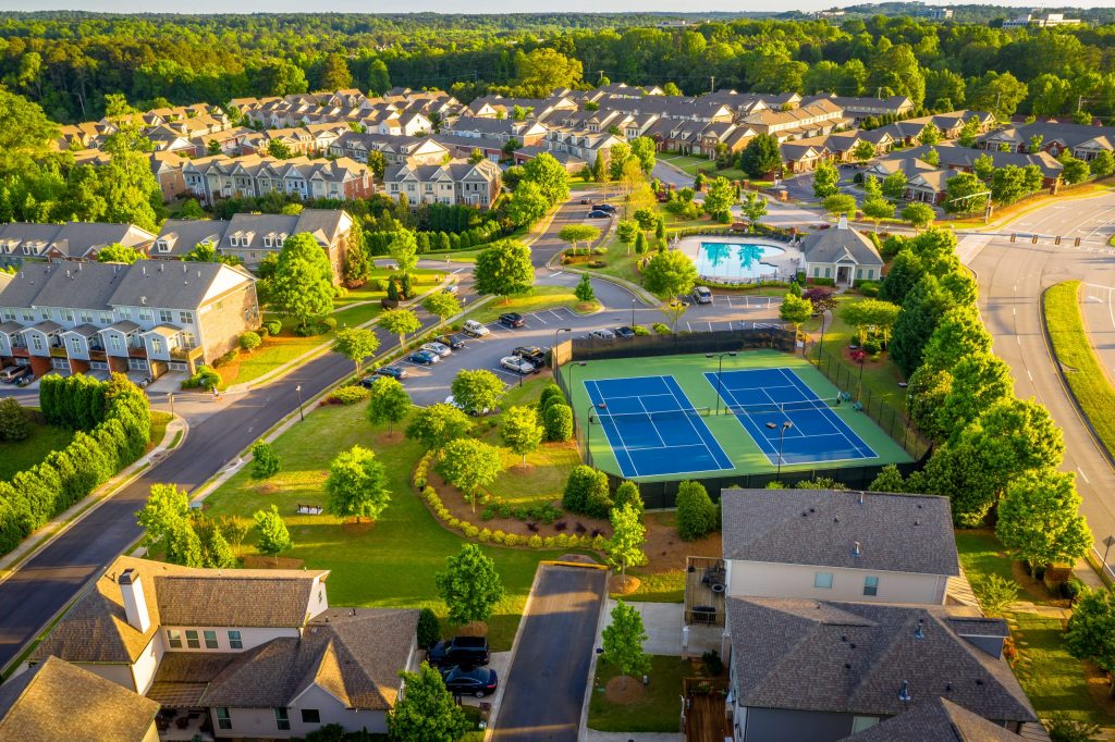 Aerial view of a well-manicured condo community with tennis courts and a pool. 