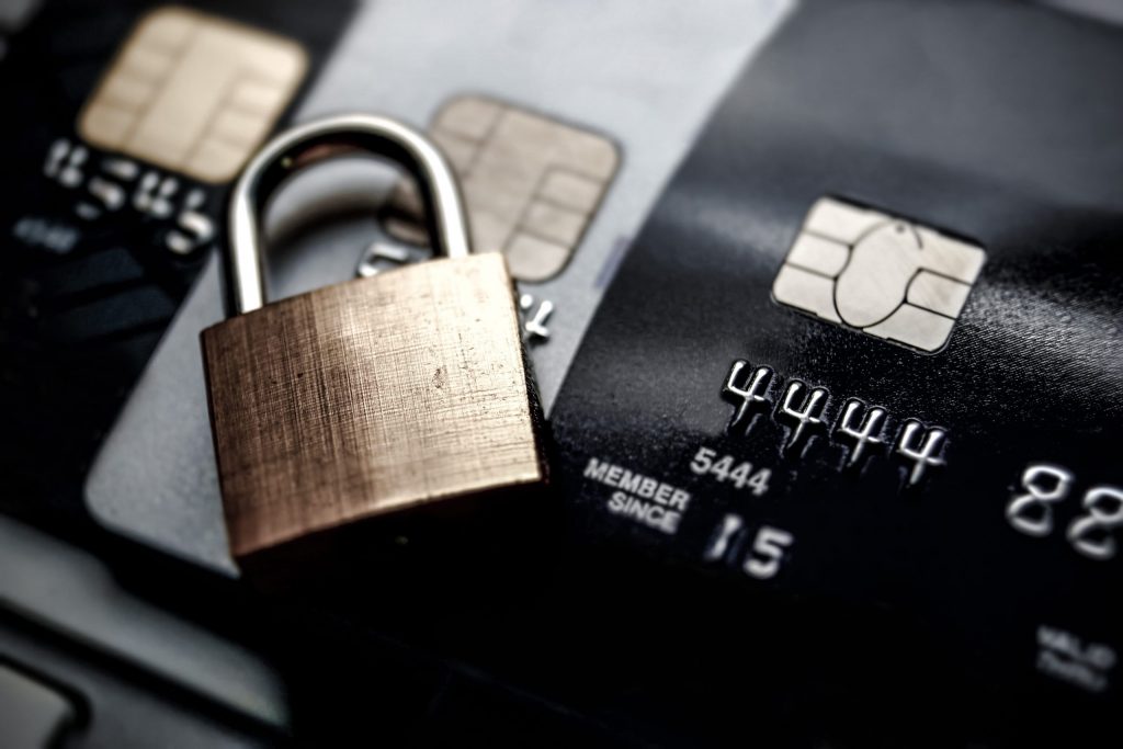  Close up of the microchip on three credit cards with a gold padlock laying on top of the credit cards. 